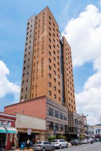 un edificio alto con auto parcheggiate di fronte a una strada di Hotel Carlton Plaza a Poços de Caldas