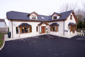 een wit huis met een zwart dak bij Woodview House Bed and Breakfast in Cork
