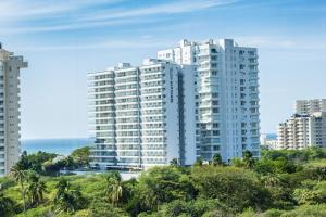 a group of tall white buildings in front of the ocean at Mercure Santa Marta Emile in Santa Marta