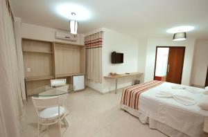 ein Hotelzimmer mit einem Bett und einem Glastisch in der Unterkunft Parati Palace Hotel in Santo Antônio de Jesus