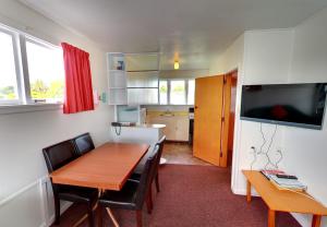 ein Esszimmer mit einem Tisch, Stühlen und einem TV in der Unterkunft Belle Bonne Motel in Christchurch