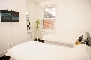 a white room with two beds and a tv at The Claremont in Southampton