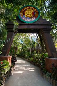 una entrada a un jardín con un cartel sobre una pasarela en Ramon's Village Resort, en San Pedro