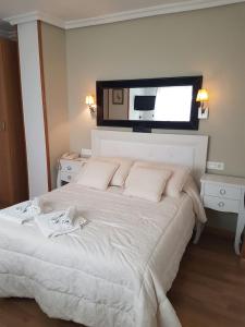 a bedroom with a white bed with a television above it at Hotel Principe in Albacete