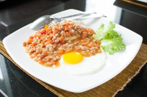 a plate of food with a fried egg and broccoli at Kasemsarn Hotel Chanthaburi in Chanthaburi