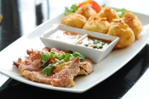 a plate of food with meat and onion rings at Kasemsarn Hotel Chanthaburi in Chanthaburi