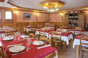 un restaurante con mesas con manteles rojos y blancos en Hotel Posta, en Issime