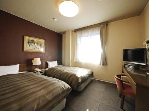 Hotel Route-Inn Court Karuizawa في Miyota: غرفة فندقية بسريرين ونافذة