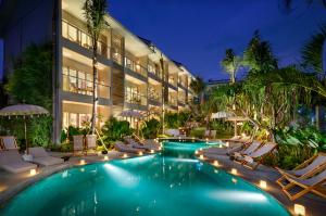 a hotel with a swimming pool with chairs and umbrellas at Canggu Beach Apartments in Canggu