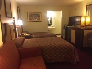 Habitación de hotel con 2 camas y TV de pantalla plana. en Maple Leaf Inn & Suites, en Kissimmee