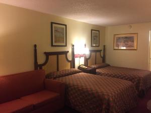 a hotel room with two beds and a couch at Maple Leaf Inn & Suites in Kissimmee