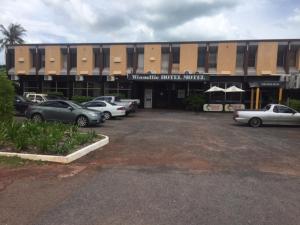 a parking lot with cars parked in front of a building at Winnellie Hotel Motel in Darwin