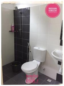 uma casa de banho com um WC, um chuveiro e um lavatório. em Wadihana Homestay em Kangar