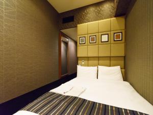 a bedroom with a large bed with white sheets at Sotetsu Fresa Inn Higashi Shinjuku in Tokyo