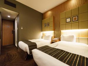 a hotel room with two beds with white sheets at Sotetsu Fresa Inn Higashi Shinjuku in Tokyo