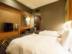 a hotel room with a bed and a television at Sotetsu Fresa Inn Higashi Shinjuku in Tokyo