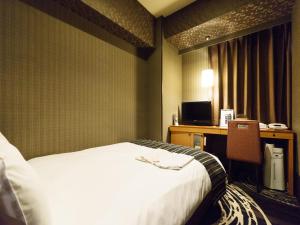 a hotel room with a bed and a desk at Sotetsu Fresa Inn Higashi Shinjuku in Tokyo