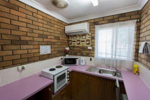 a pink kitchen with a sink and a microwave at Park House Motor Inn in Oakey