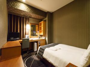 a hotel room with a bed and a desk with a computer at Sotetsu Fresa Inn Higashi Shinjuku in Tokyo