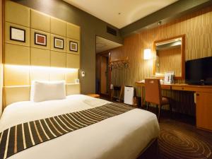 a hotel room with a large bed and a desk at Sotetsu Fresa Inn Higashi Shinjuku in Tokyo
