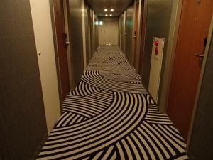 a long corridor with black and white stripes at Sotetsu Fresa Inn Higashi Shinjuku in Tokyo