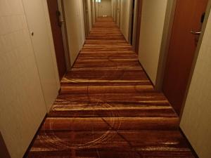 a long hallway with wooden floors in an office building at Sotetsu Fresa Inn Higashi Shinjuku in Tokyo