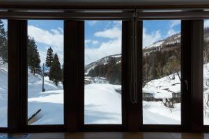 una ventana con vistas a una montaña nevada en Nozawa House, en Nozawa Onsen