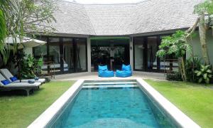 una piscina frente a una casa con almohadas azules en Duke's Bingin Villas, en Uluwatu