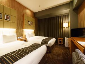 a hotel room with two beds and a television at Sotetsu Fresa Inn Higashi Shinjuku in Tokyo