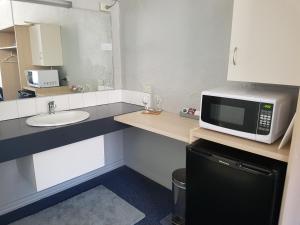 a small kitchen with a microwave and a sink at Belmore Motor Inn in Yarrawonga