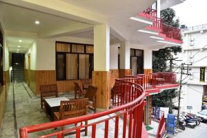 un edificio con barandilla roja, mesas y sillas en Hotel Akash en McLeod Ganj