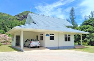 a small white house with a car parked in it at Wyn Villa in Anse Possession