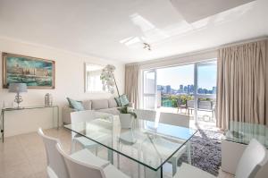 a living room with a glass table and white chairs at 3 Canterbury Square in Cape Town