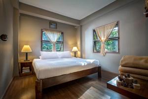 a bedroom with a bed and two windows at Khaokhoherbary OrganicFarm&Resort in Khao Kho