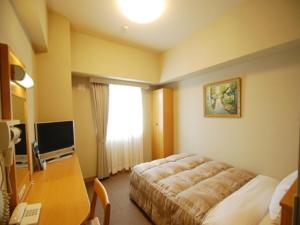 Dormitorio con cama, escritorio y TV en Hotel Route-Inn Yukuhashi, en Yukuhashi