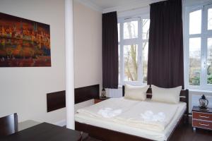 una camera da letto con un letto con lenzuola bianche e due finestre di MY-BED Hamburg ad Amburgo