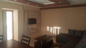 a living room with a table and a tv on the wall at Pestani Apartment in Peštani