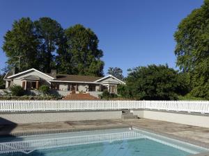 a house with a white fence and a swimming pool at Notting Hill Lodge in Nottingham Road