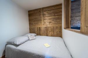 a small bedroom with a bed with a wooden wall at Meribel 17 in Méribel