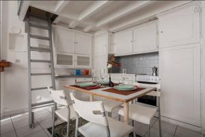 ボルドーにあるAppartement Boucheries Centre Villeの白いキャビネット、テーブルと椅子付きのキッチンが備わります。