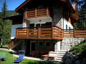 a house with a balcony and a table and chairs at Chalet Villa Bianca in Tesero