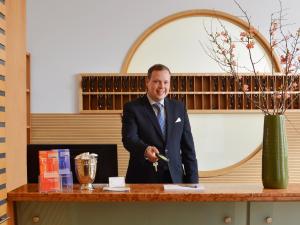 Ein Mann im Anzug steht an einem Tisch in der Unterkunft Hotel Ludwig Superior in Köln