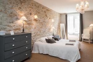 カルカソンヌにあるLa Maison Vieille Maison d'Hôtes & Gîtesの白いベッドと石の壁が備わるベッドルーム1室