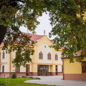 duży żółty budynek z krzyżem na górze w obiekcie MAMRE Szálló w mieście Hajdúböszörmény
