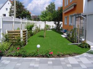 un jardín con una valla blanca y césped verde en Ferienhaus Gumann en Núremberg