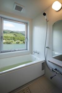 a bathroom with a bath tub and a window at Satorikan in Gosen