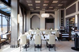 une salle à manger avec des tables et des chaises blanches dans l'établissement Ambassadeurs Logis Hotel, à Saint-Malo
