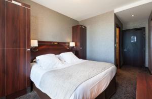 sypialnia z dużym łóżkiem z białą pościelą i poduszkami w obiekcie Ambassadeurs Logis Hotel w Saint-Malo