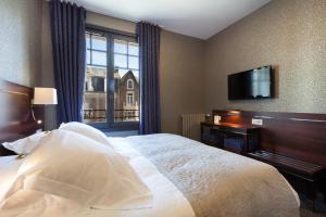 a hotel room with a bed and a flat screen tv at Les Ambassadeurs, Logis Hotel, sa crêperie et son rooftop - Saint Malo Plage in Saint Malo +46 photos