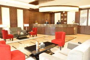 a lobby with red chairs and a bar with two people at Thwary Hotel Suites in Riyadh